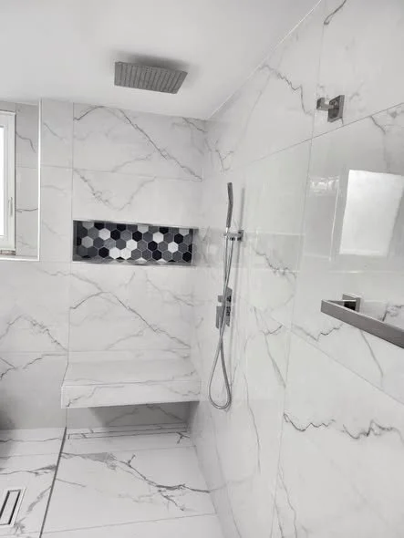 Detail of slab-matched marble shower wall with hexagon mosaic accent
